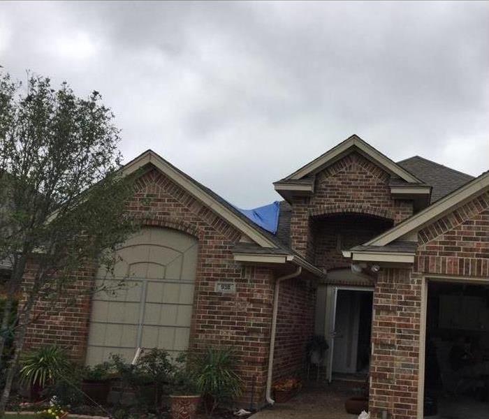 blue tarp covering fire damaged roof of home